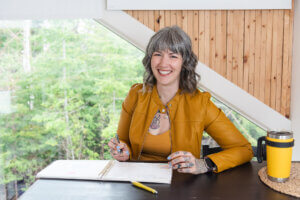 woman wearing mustard sitting at a desk journalling