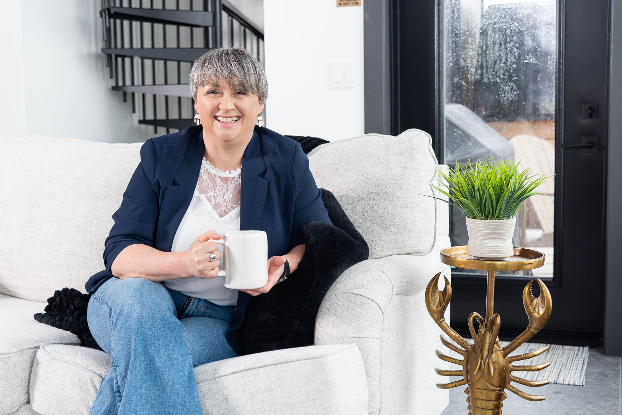 Maritime business women on the sofa holding a cup of coffee with a lobster based table beside