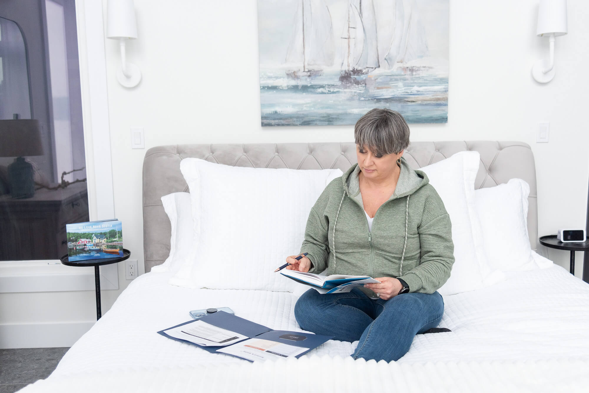 branding photo of a service based woman working on a bed with sheets and books around her