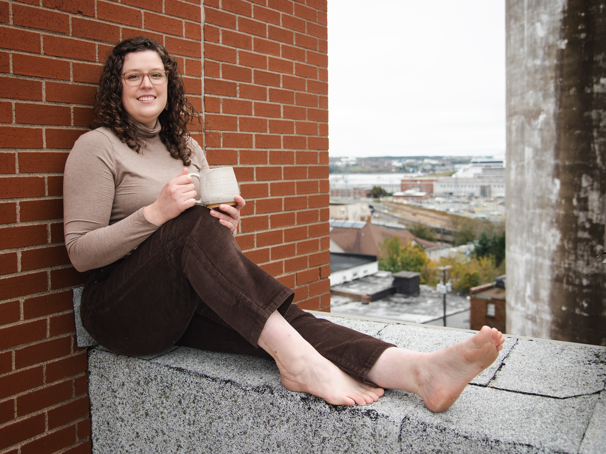 female with dark hair and coffee mug on rooftop with a view of the Harbour during Halifax Brand Photography shoot with Dandelion Digital