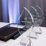 3 glass CAPSI awards and 2 black certificate folios on table
