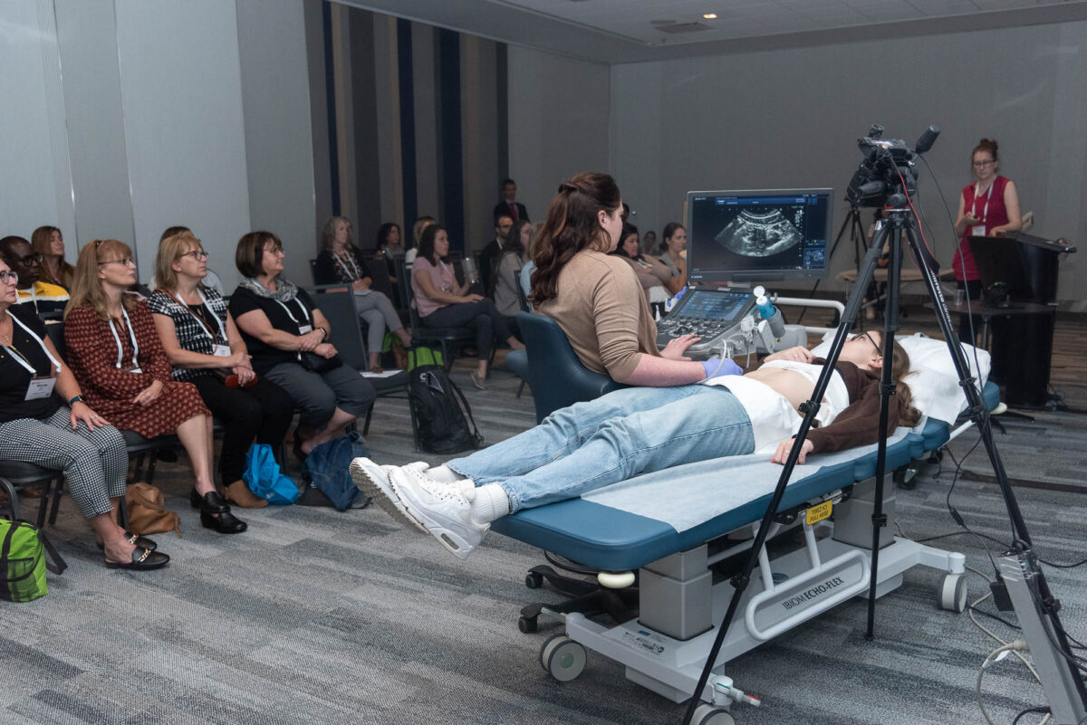 woman laying on gurney having ultrasound taken as technicians watch and learn in breakout room of lower salon, Halifax Convention centre
