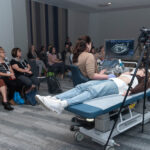 woman laying on gurney having ultrasound taken as technicians watch and learn in breakout room of lower salon, Halifax Convention centre
