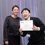 an asian man in suit laughing as he receives event award