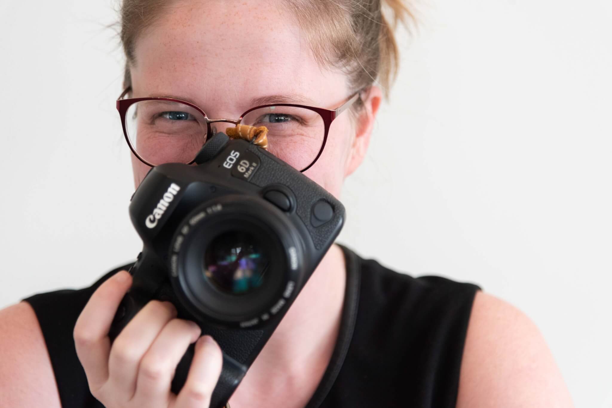 a female photographer holding Cannon camera in front of face