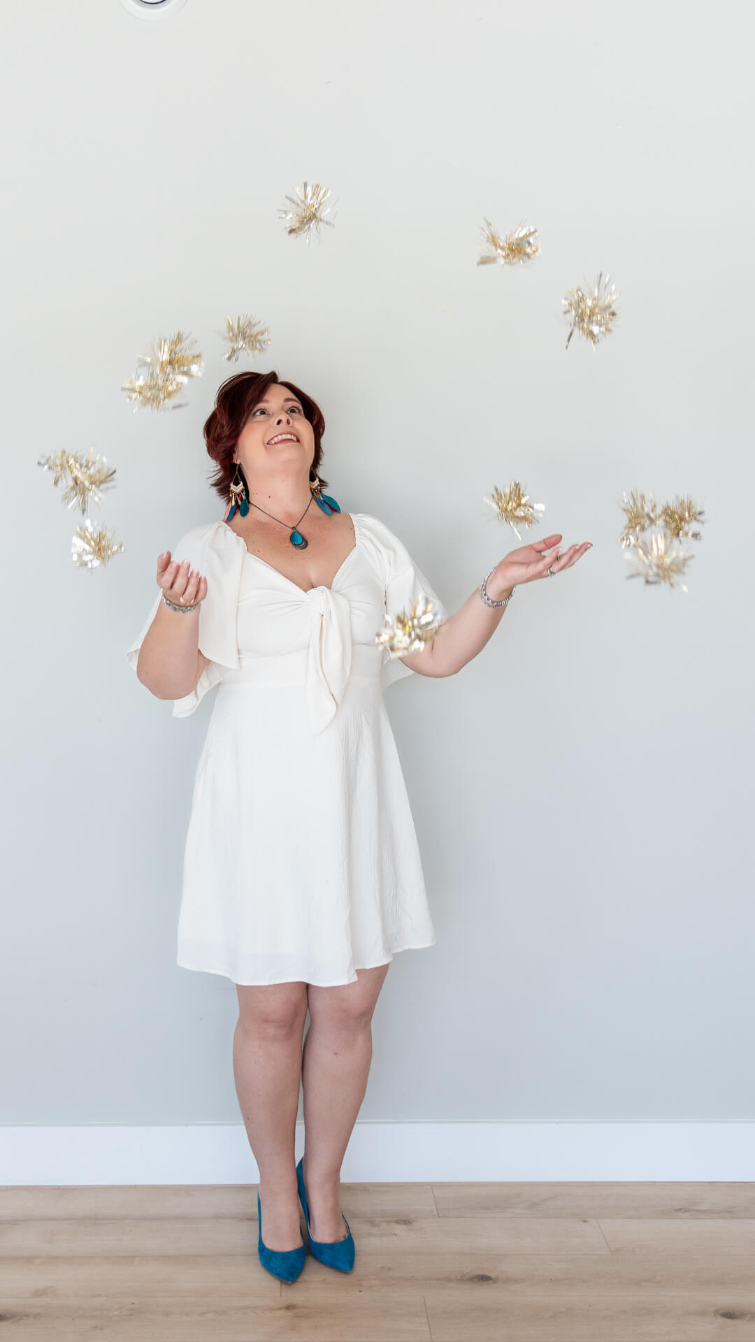 Resilience coach laughs while tossing gold confetti overhead, capturing energy and joy for her brand photography.