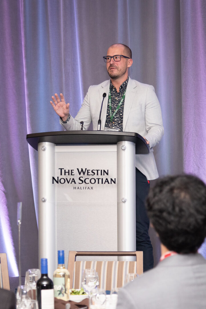 man at podium in Westin Nova Scotian Hotel ballroom giving keynote