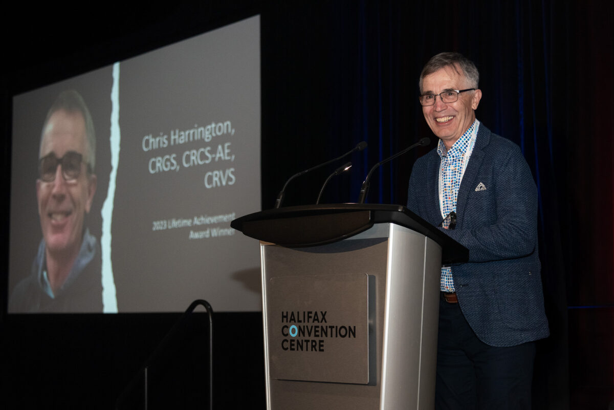 man smiling on stage at Sonography Canada conference as her receives Lifetime Acheivement Award
