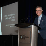 man smiling on stage at Sonography Canada conference as her receives Lifetime Acheivement Award