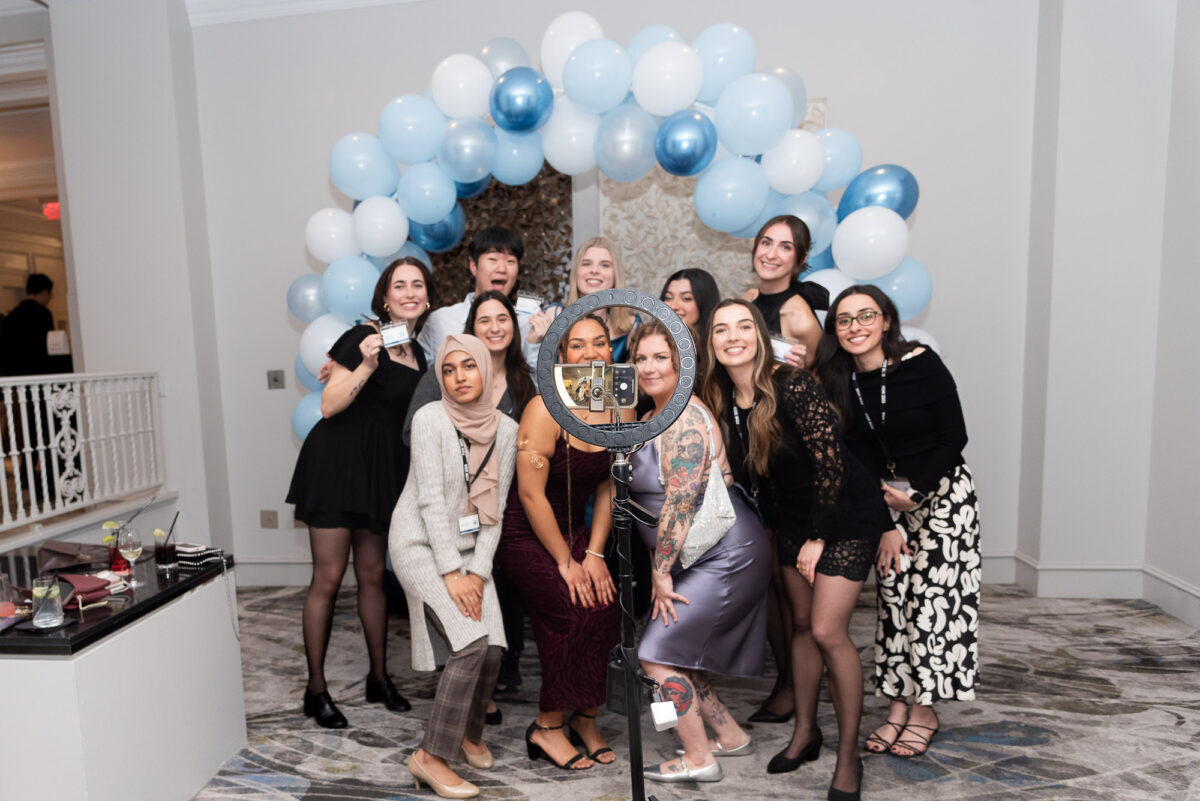 group of women under a ballon arch taking a selfie with ring light stand