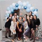 group of women under a ballon arch taking a selfie with ring light stand