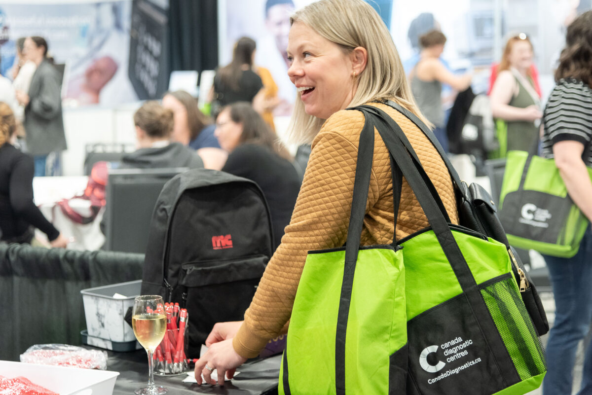 woman reacting hppily at trade show booth, carrying swag bag