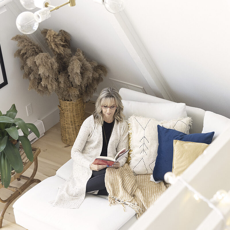 Nicole, Founder of SmartCat Marketing, curled up on couch reading A Story brand book