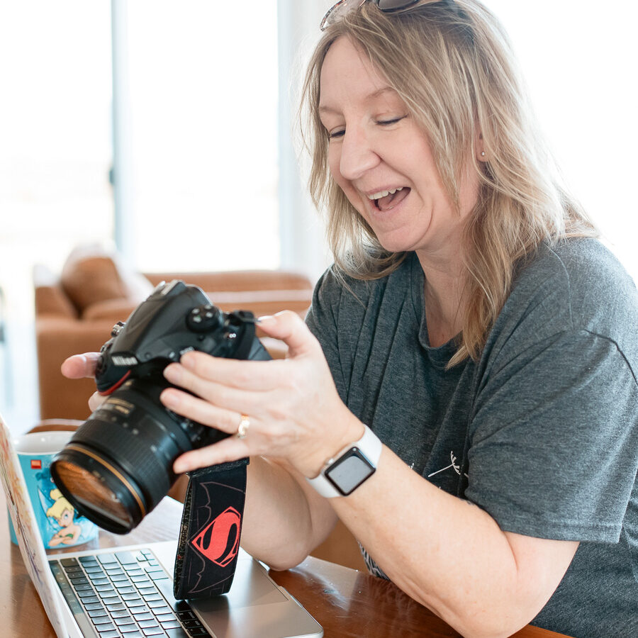 blond female photographer laughing while looking at the back of her camera